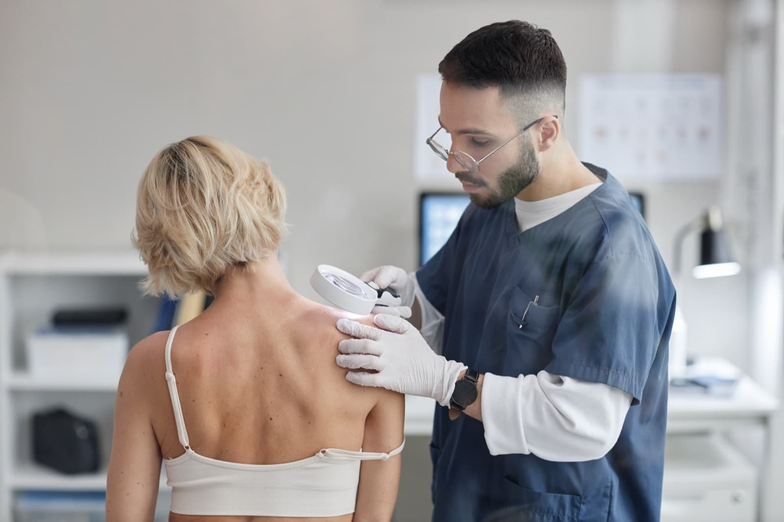 Dermatologista examinando a pele de uma paciente em consultório