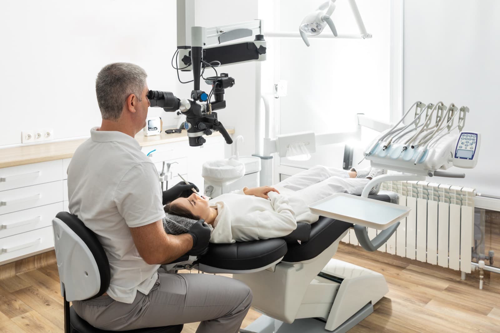 Dentista utilizando microscópio odontológico durante atendimento